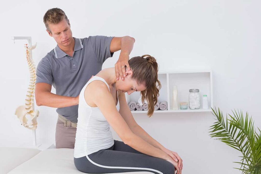 A chiropractor discussing spinal health and wellness routines with a local adult in a comfortable clinic setting.