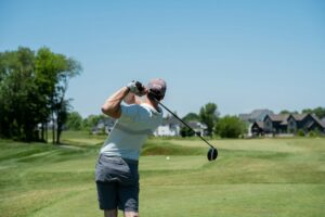 Golfer performing a controlled warm-up rotation beside a practice area before swinging a club.
